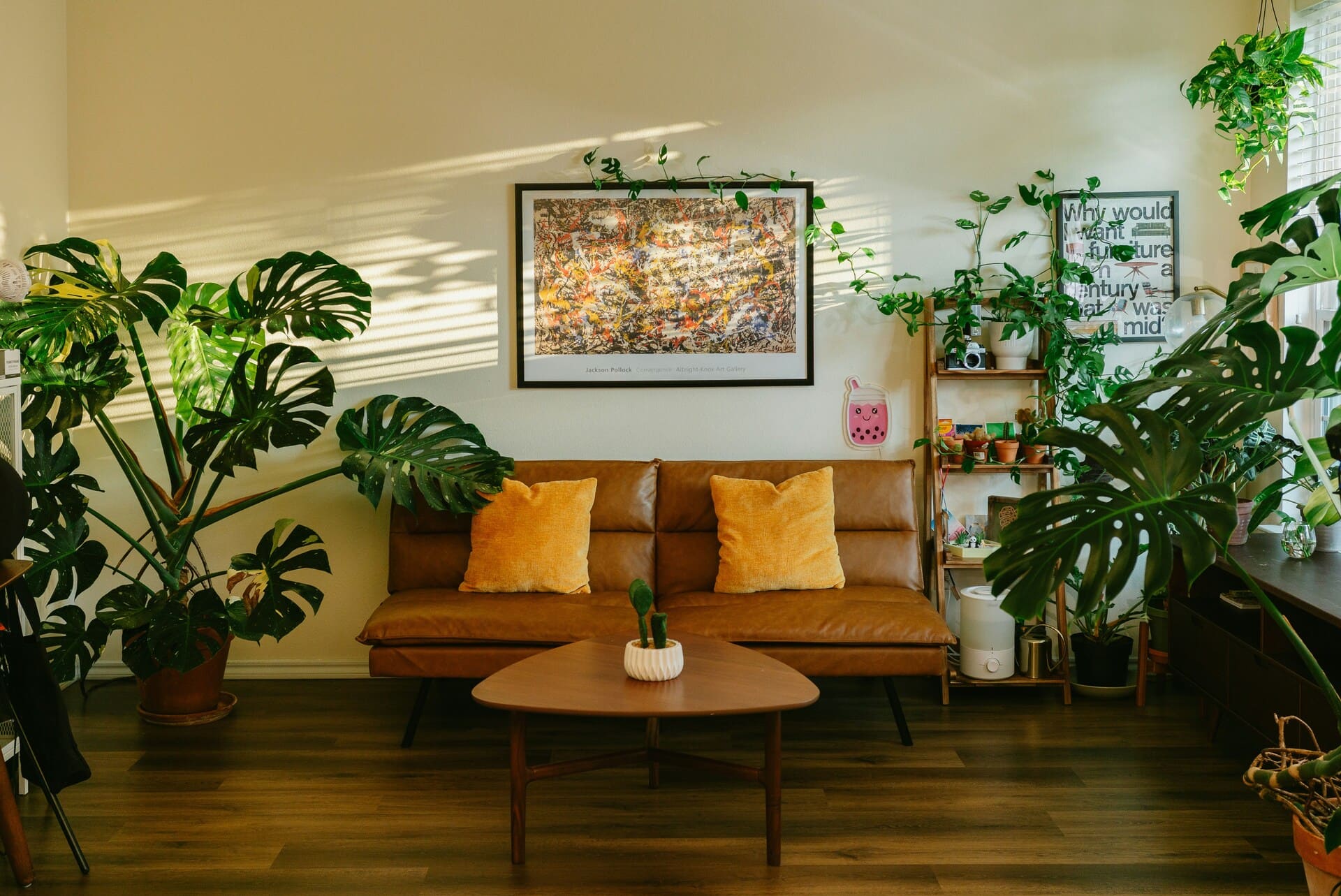 salon z dużymi oknami skórzana sofa rośliny drewniany stolik