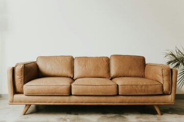 skórzana sofa trzyosobowa nowoczesny design beżowa ściana roślina