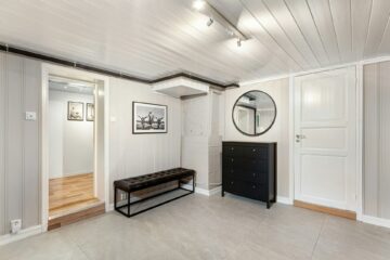 przedpokój z czarną komodą ławką i okrągłym lustrem